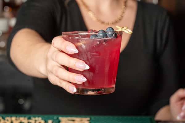 Bartender holding a cocktail garnished with blueberries