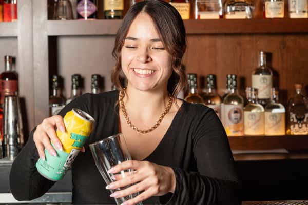 Bartender pouring a drink from a can into a glass