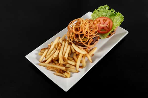 Classic cheeseburger topped with crispy onion straws, lettuce, and tomato, served with a side of seasoned fries on a white plate.