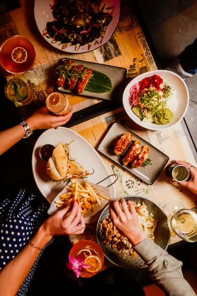 Guests enjoying sushi, shareable plates, and craft cocktails at Kapow! Noodle Bar, showcasing a vibrant modern Asian fusion dining experience in Boca Raton and Delray Beach.