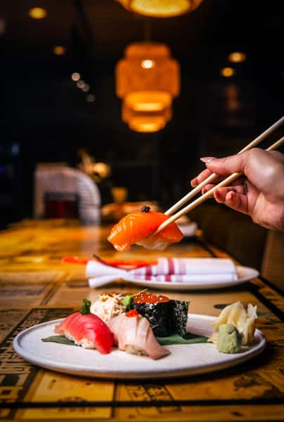 Fresh salmon nigiri sushi being served at Kapow! Noodle Bar, showcasing premium Asian fusion dining and expertly crafted sushi in Boca Raton and Delray Beach.