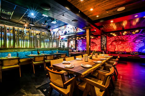 Modern dining room at Kapow! Noodle Bar featuring dramatic artwork, warm lighting, and a sophisticated setting for sushi, cocktails, and Asian fusion dining.
