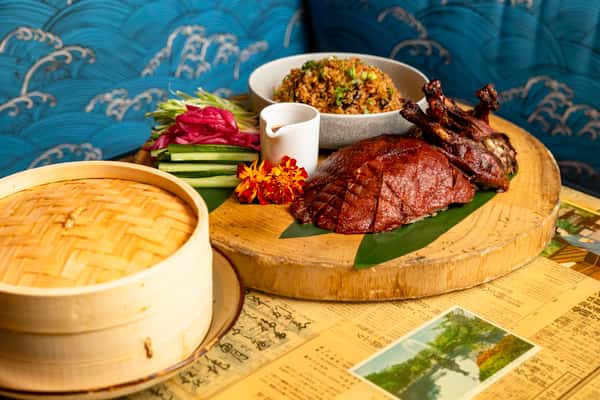 Signature Peking duck platter with steamed buns, fresh accompaniments, and Asian fusion sides at Kapow! Noodle Bar, perfect for sharing and special occasions.