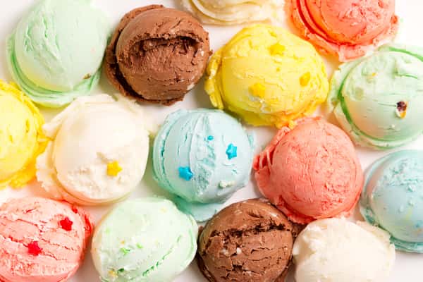 Colorful assorted ice cream scoops with star-shaped sprinkles arranged on a white background.