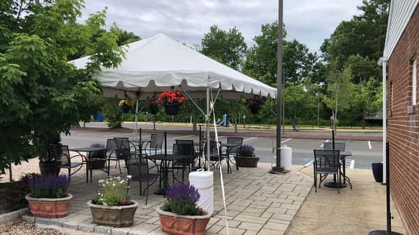 Outside seating of tables and chairs with a tent on the side walk