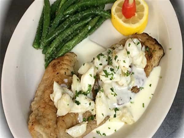 fried dish with white sauce on top and string beans on the side