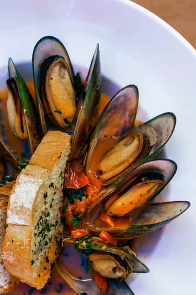 Steamed mussels in a savory tomato and white wine broth served with toasted bread, a classic Italian seafood dish.
