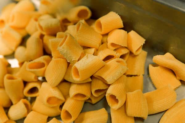 Close-up of uncooked rigatoni pasta on a metal tray in an Italian kitchen, showcasing ridged tubular pasta ready for classic Italian dishes.