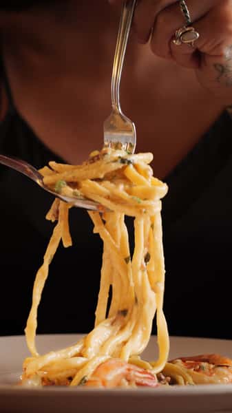 Fork twirling creamy shrimp linguine above a bowl of pasta, highlighting tender shrimp and silky Italian garlic cream sauce.