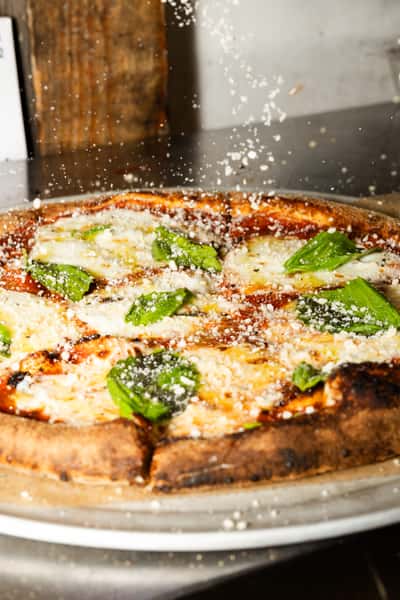 Sprinkling parmesan on a classic Fogtown margherita pizza