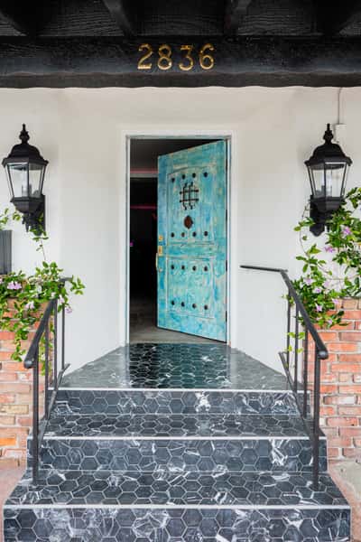 Exterior entry way with marbled flooring and a light blue distressed door