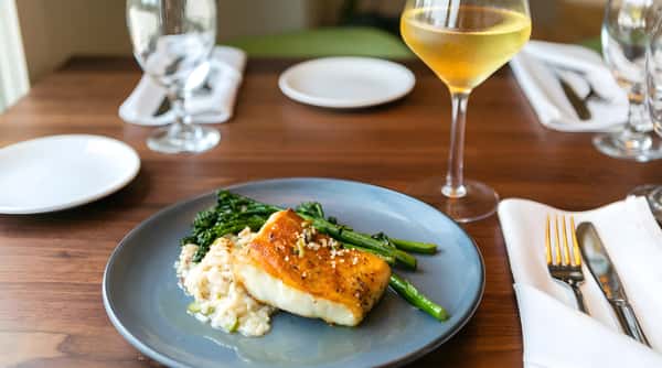 Pan-seared fish served with mashed potatoes, green beans, and a cocktail.
