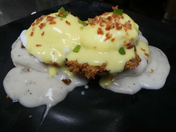 Fried chicken eggs Benedict topped with poached eggs, hollandaise, and bacon bits over biscuits and creamy sausage gravy.