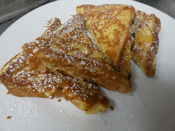 Thick-cut French toast triangles dusted with powdered sugar, served golden brown and perfectly crisp on the edges.