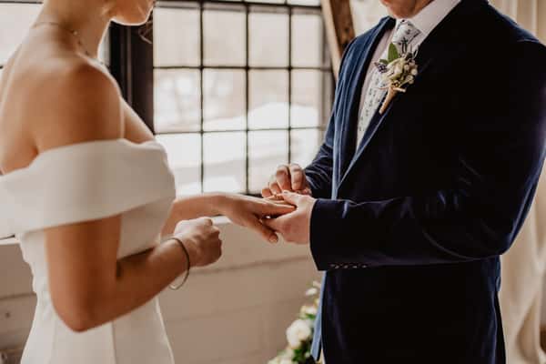 man putting ring on bride's finger
