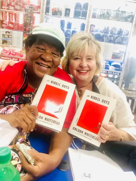 two women holding "Nickel Boys" books by Colson Whitehead inside Melba's with bookstore shelves and community vibe