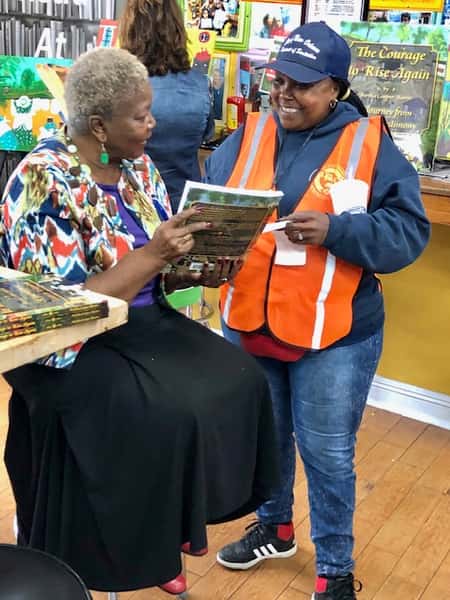 author signing books for guest inside Melba's restaurant bookstore with warm community atmosphere and literary event setting