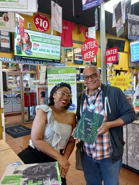 author and guest posing with book inside Melba's restaurant bookstore with "Free Books" signs and lively community reading event atmosphere