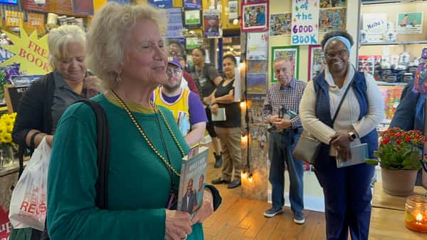guest speaking during book event at Melba's restaurant while holding book, with audience gathered in cozy bookstore dining space
