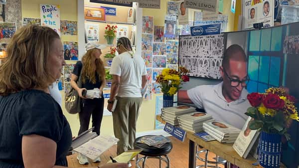customer browsing books near display and TV at Melba's restaurant bookstore with flowers and featured author setup