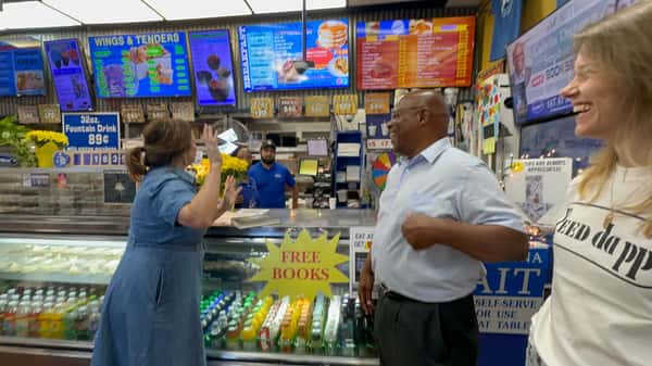 customers celebrating at Melba's Southern restaurant counter with "Free Books" sign and colorful menu boards overhead