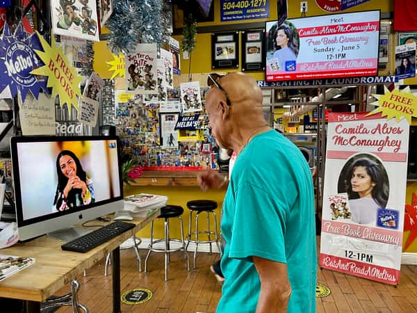 guest watching virtual author event at Melba's restaurant bookstore with "Free Books" displays and Eat and Read signage