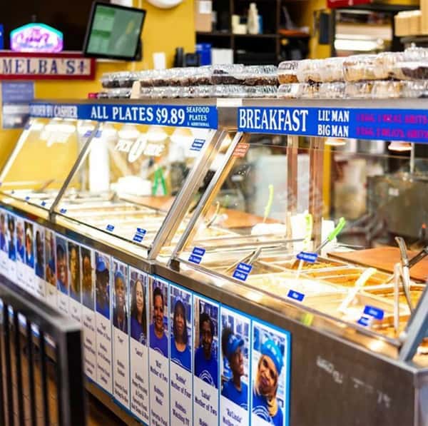 cafeteria-style soul food counter at Melba's restaurant with hot buffet trays, breakfast menu signage, and Southern comfort dishes on display