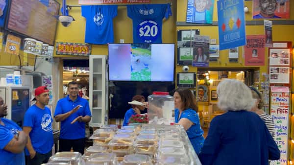 Melba's team gathered behind counter with Southern takeout trays and vibrant restaurant decor during community event