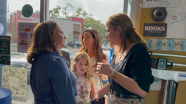 group of women and child chatting near entrance of Melba's restaurant with "Free Books" signage and neighborhood dining atmosphere