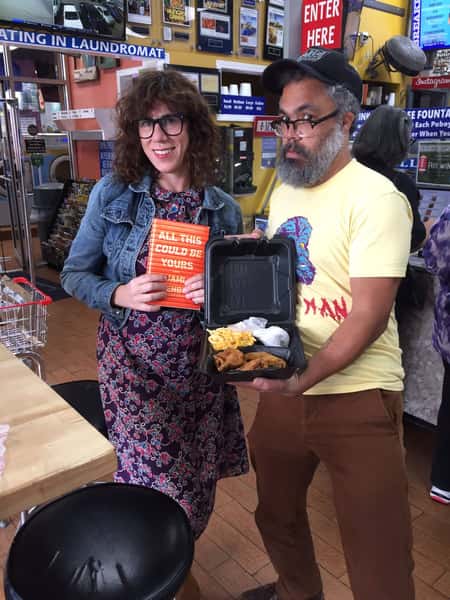 customers posing inside Melba's restaurant with Southern fried chicken, mac and cheese takeout, and book during community dining experience