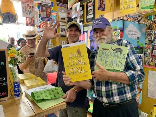 guests holding children's books inside Melba's restaurant bookstore during lively community reading event