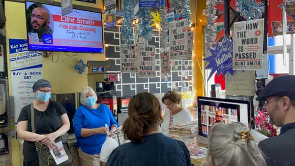community gathered inside Melba's restaurant watching virtual Clint Smith reading surrounded by book displays and festive decor