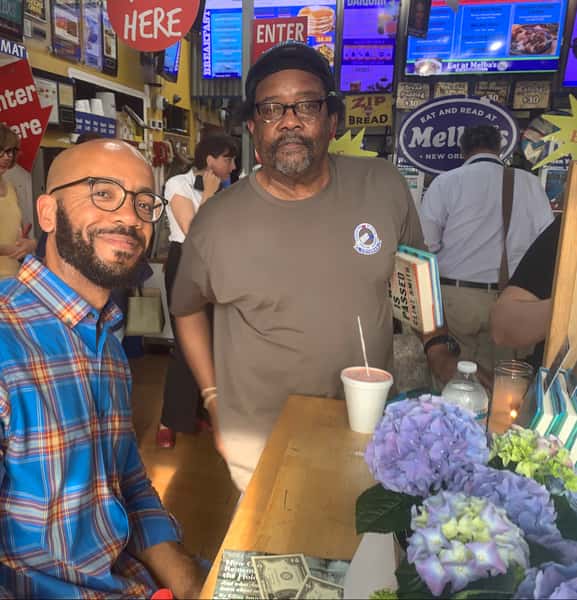 two guests smiling at Melba's restaurant holding books during community reading event with "Eat and Read" signage