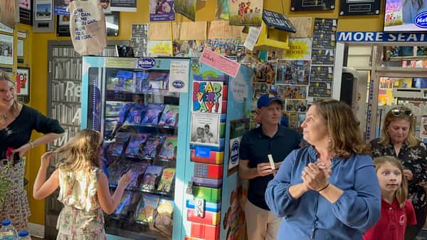 family and guests gathered around Melba's book vending machine with "Read Every Day" sign during community literacy event