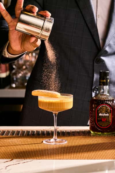 Bartender adding a dusting of spice to a cocktail