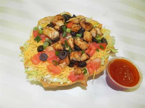 Personal pizza topped with lettuce, tomatoes, shredded cheese, olives, and chicken