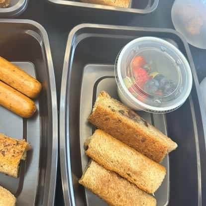 Tray with toasted bread sticks and a small cup of mixed berries including strawberries, blueberries, and grapes.