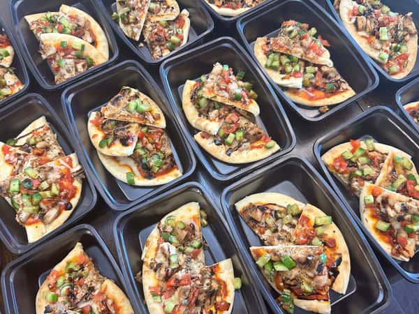 Individual meal prep containers with flatbread pizzas topped with grilled chicken, green peppers, tomatoes, and barbecue drizzle.