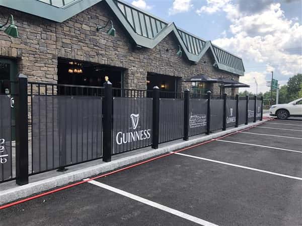 exterior fence to the irish cottage with the establishments logo and guinness logo printed on banners
