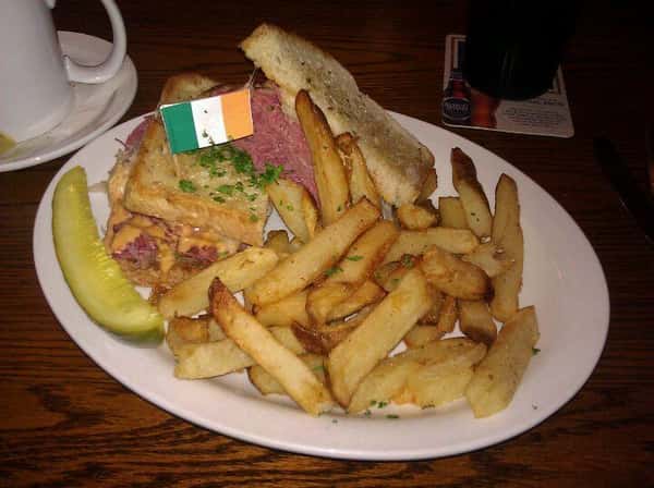 reuben sandwich with a side of french fries and a pickle spear