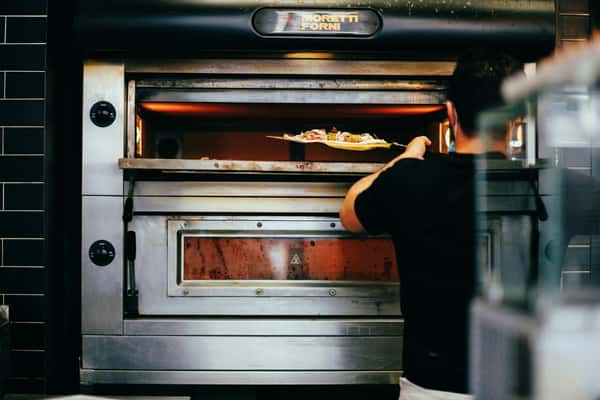 Inserting pizza into oven to bake