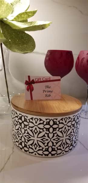 a candle with a prime rib gift card sitting on top