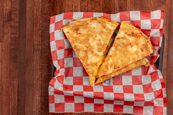 Quesadilla cut into wedges with a golden-brown tortilla, served on red-and-white checkered paper.