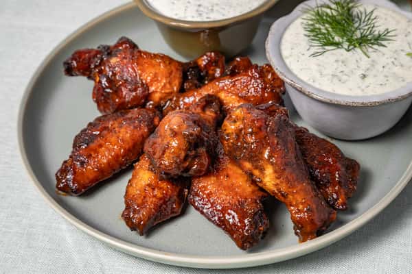 Glazed chicken wings served on a ceramic plate with sides of creamy herb ranch and dill dip—ideal for game day menus, BBQ platters, or casual Southern dining.