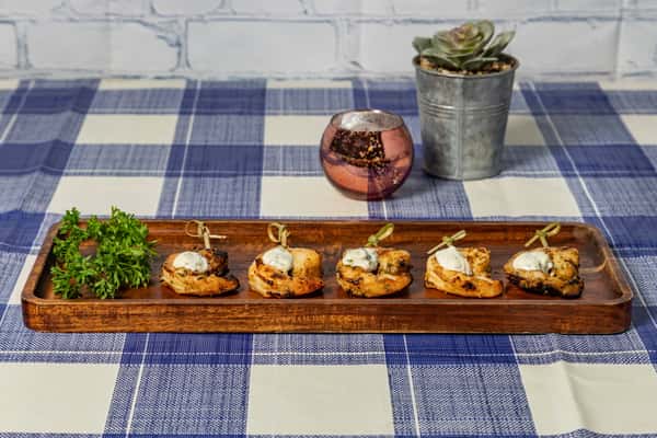 Grilled shrimp appetizers served on toasted bread rounds, topped with herbed cream sauce and garnished with parsley, presented on a rustic wooden tray—perfect for elegant Southern hors d'oeuvres.