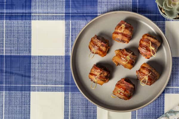 Bacon-wrapped smoked pork bites secured with toothpicks, served on a matte gray plate—perfect for savory appetizers or Southern-inspired hors d'oeuvres.