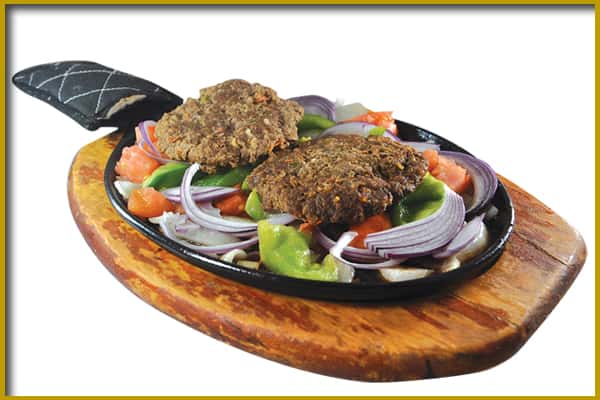 two patties over mixed vegetables in a skillet