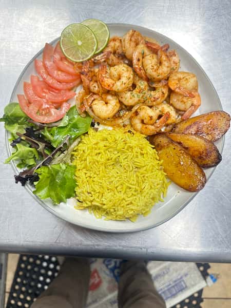 Latin cuisine plate features seasoned shrimp, fried plantain, and yellow rice. Served with a side salad and tomato and lime garnish.