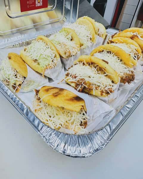 A tray of cheesy arepas. These Venezuelan corncakes are filled with savory meats and topped with shredded cheese.