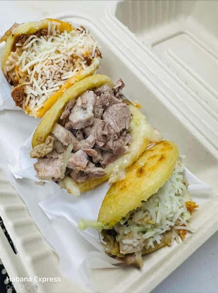 This image contains three arepas: one with shredded beef and cheese, one with pork, and one with a white shredded topping. It is of "Habana Express Cuban Restaurant & Bakery" menu items.